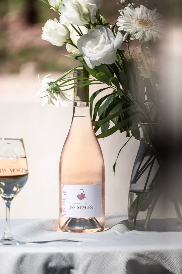 Côtes de Provence rosé photographié au printemps, à coté d'un bouquet de fleurs blanches, au domaine Jas Monges
