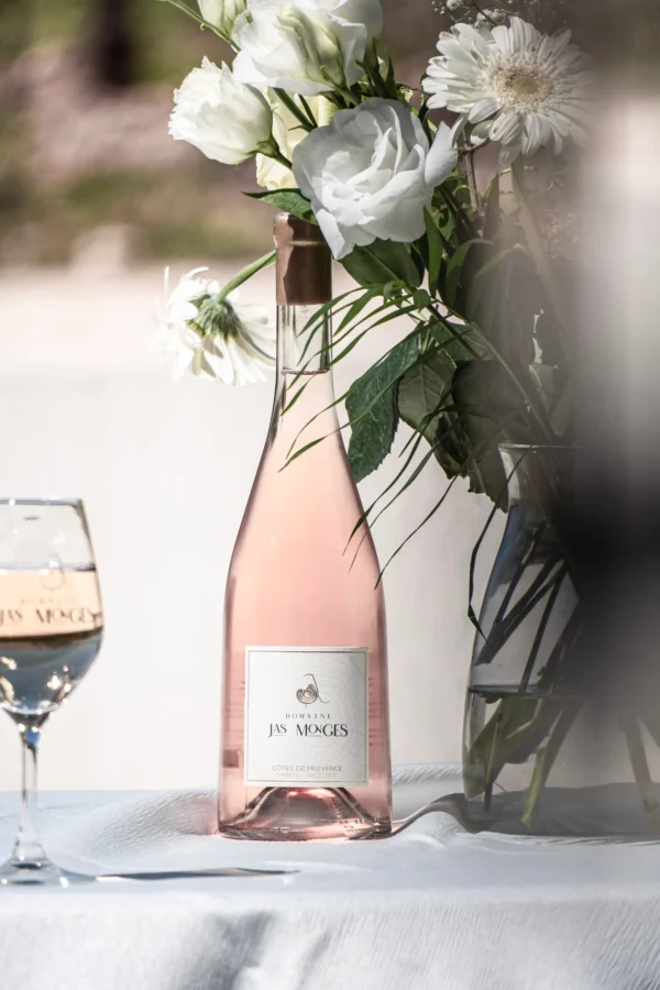 Rosé de garde photographié au printemps, à coté d'un bouquet de fleurs blanches, au domaine Jas Monges
