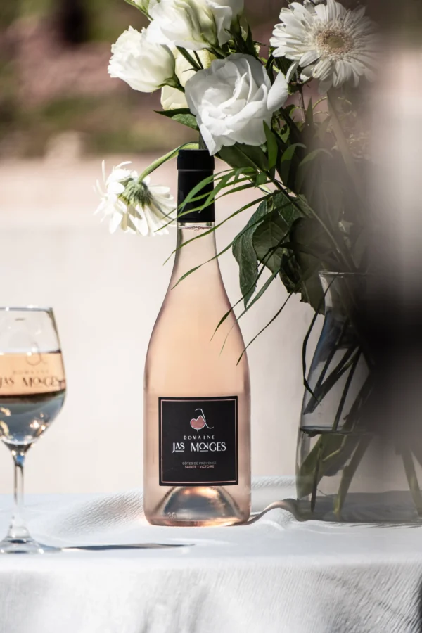 Sainte Victoire rosé photographié au printemps, à coté d'un bouquet de fleurs blanches, au domaine Jas Monges