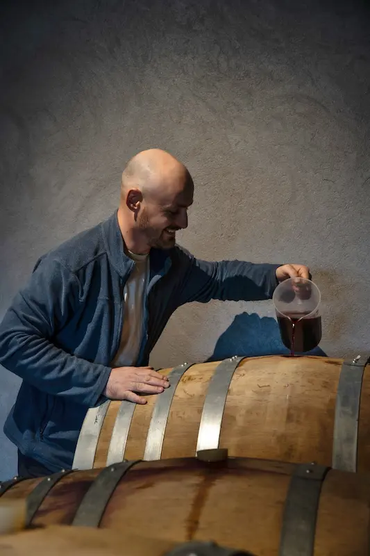Etape de vinification d'un vin en barrique avec une éprouvette par l'oenologue du domaine